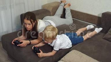 年轻的母亲和一个小儿子在家里的沙发上<strong>玩电脑</strong>游戏